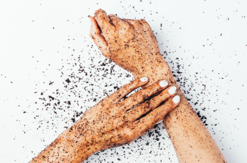 A person exfoliating their arms with an exfoliant