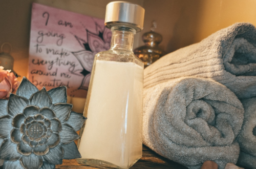 a bottle of homemade non-toxic laundry detergent next to clean towels