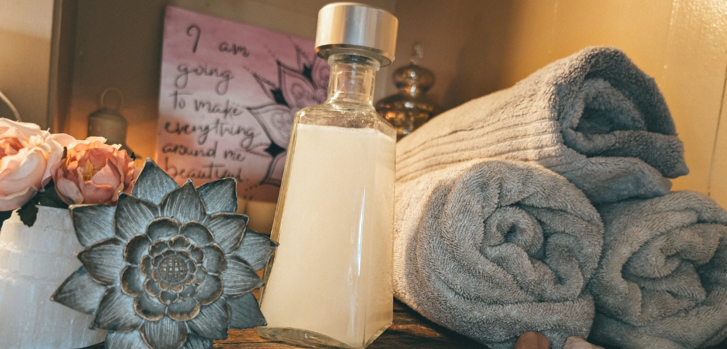 a bottle of homemade non-toxic laundry detergent next to clean towels