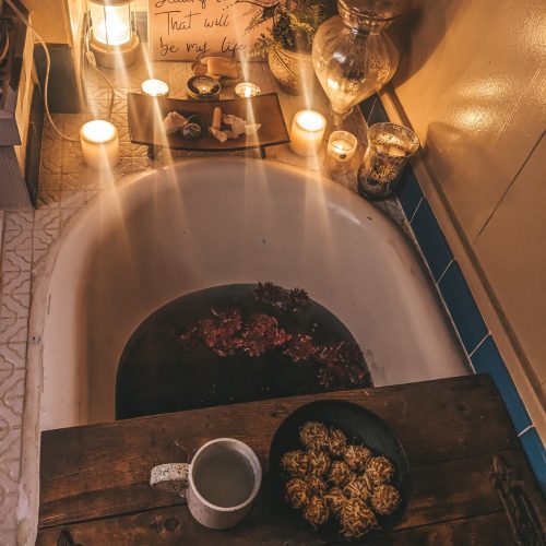 New Moon Ritual Bath with candles, crystals, ayurvedic sweets, hot tea, and midnight dahlias.