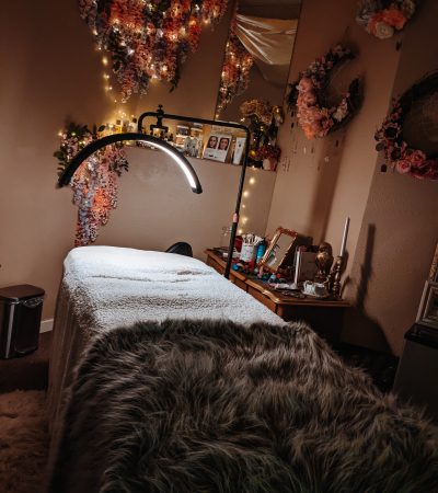 A magical image with fairy twinkle lights and hanging wisteria of a luxury esthetics spa room and a half moon spa lamp