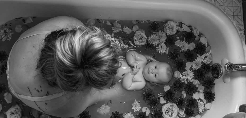 Mother and baby in a decorative floral bath in black and white for a Rebirthing Ritual.