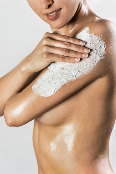 A woman exfoliating with a body scrub